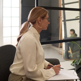 Mujer trabajando y tomando notas en una oficina luminosa.