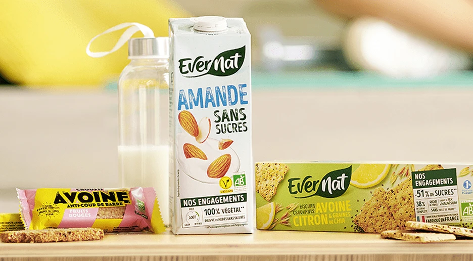 Bebida vegetal de almendra y snacks ecológicos Evernat sobre una mesa.