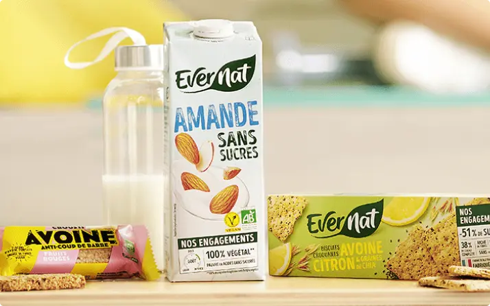 Bebida vegetal de almendra y snacks ecológicos Evernat sobre una mesa.